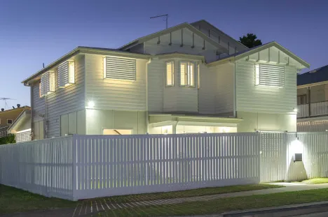 Well-lit modern white two-story house at dusk